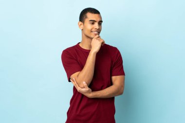 Afrikalı Amerikalı bir adam izole edilmiş arka planda, yana bakıyor ve gülümsüyor.