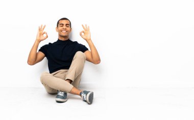 Zen pozuyla yerde oturan Afrikalı Amerikalı bir adam.