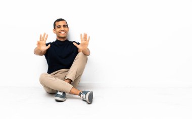 Afro-Amerikalı adam yerde oturmuş parmaklarıyla dokuza kadar sayıyor.