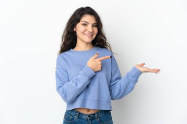 Beyaz arka planda izole edilmiş genç bir Rus kızı, bir ilan vermek için avucunda hayali bir mekan tutuyor.