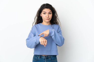 Beyaz arka planda izole edilmiş genç Rus kız geç kalma jesti yapıyor.