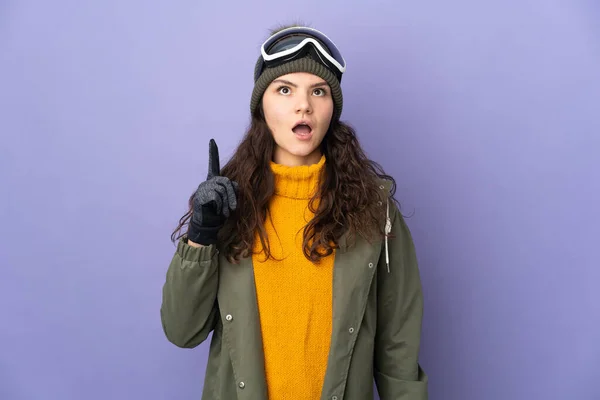 年轻的俄罗斯女孩 戴着雪板眼镜 背景是紫色的 她想用手指指尖 — 图库照片