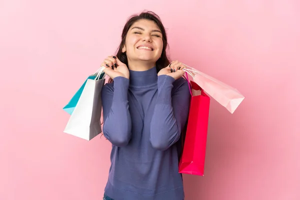 ティーンロシアの女の子隔離された上のピンクの背景保持ショッピングバッグと笑顔 — ストック写真