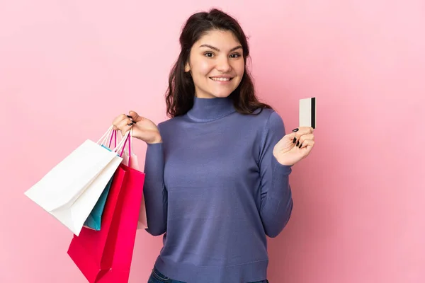 ティーネージャーロシアの女の子孤立した上ピンクの背景保持ショッピングバッグとクレジットカード — ストック写真