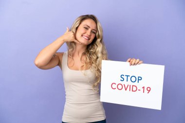 Mor arka planda izole edilmiş genç Brezilyalı bir kadın elinde yazılı bir levhayla Covid 19 'u durdur ve telefon hareketi yap.