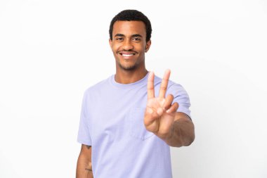 Afro-Amerikalı yakışıklı adam izole edilmiş beyaz arka planda gülümsüyor ve zafer işareti gösteriyor.