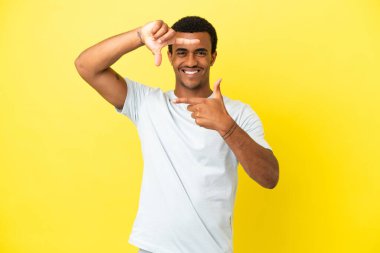 İzole edilmiş sarı arka planda odaklanan yakışıklı Afro-Amerikalı bir adam. Çerçeve sembolü