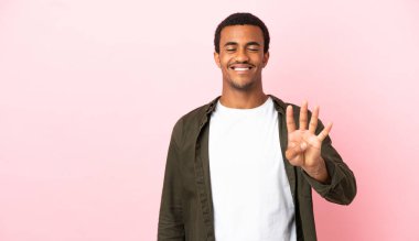 Telif uzayındaki Afro-Amerikalı adam pembe arka planda mutlu ve parmaklarıyla dört sayıyor