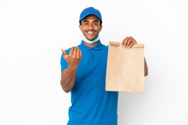 Afro-Amerikalı bir adam, beyaz arka planda izole edilmiş bir paket yiyecek alıyor ve bizimle gelmesi için davet ediyor. Gelmene sevindim.