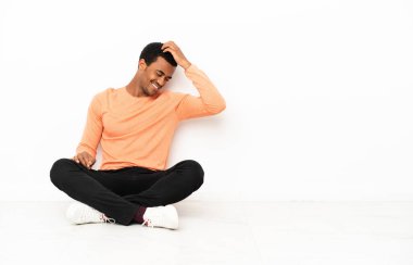 Afrikalı Amerikalı bir adam izole edilmiş arka planda oturmuş gülüyor.