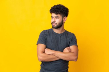 Faslı genç bir adam sarı arka planda izole edilmiş, yana bakıyor.