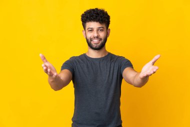 Sarı arka planda izole edilmiş genç Faslı adam sunar ve davet eder.