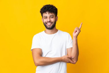 Sarı arka planda izole edilmiş genç Faslı adam mutlu ve dik duruyor.