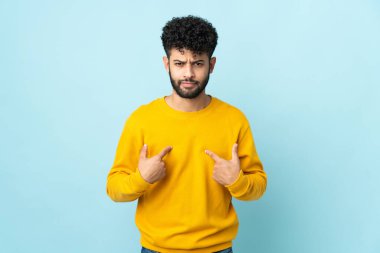 Mavi arka planda izole edilmiş genç Faslı adam kendini işaret ediyor.