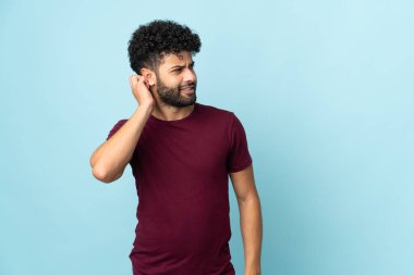 Genç Faslı bir adam mavi arka planda izole edilmiş bir fikir düşünüyor.