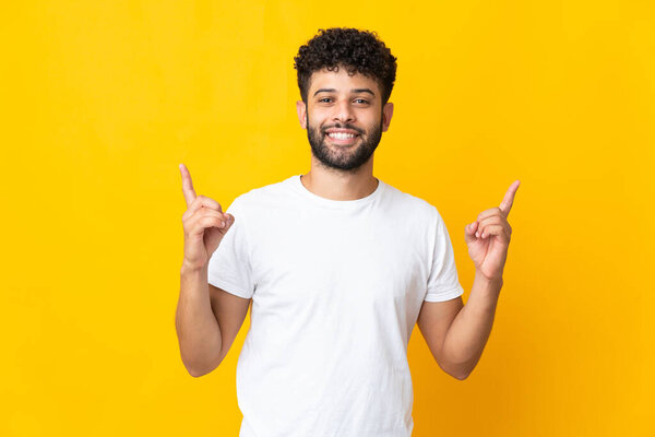 Young Moroccan man isolated on yellow background pointing up a great idea