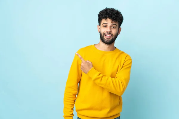 Joven Hombre Marroquí Aislado Sobre Fondo Azul Sorprendido Apuntando Lado — Foto de Stock