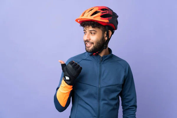 Joven Ciclista Marroquí Aislado Sobre Fondo Púrpura Apuntando Hacia Lado — Foto de Stock