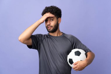 Mor arka planda izole edilmiş yakışıklı Faslı genç futbolcu yan tarafa bakarken sürpriz jest yapıyor.