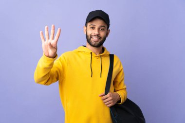Spor çantalı genç Faslı adam mor arka planda izole edilmiş mutlu ve parmakları olan dört kişi sayıyor.