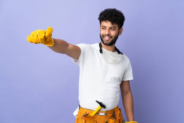 Genç elektrikçi Faslı adam mor arka planda izole edilmiş bir şekilde baş parmak hareketi yapıyor.