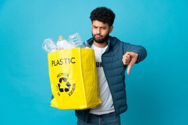 Genç Faslı bir adam, izole edilmiş arkaplanı geri dönüştürmek için elinde plastik şişelerle dolu bir çanta tutuyor.