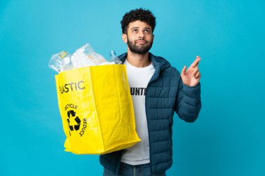 Elinde plastik şişelerle dolu bir çanta tutan genç Faslı adam izole edilmiş arka planda en iyisini diliyor.