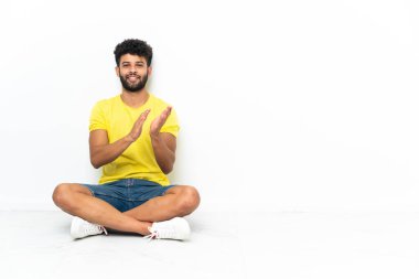 Genç Faslı yakışıklı adam izole bir arka planda oturmuş konferanstan sonra alkışlıyor.