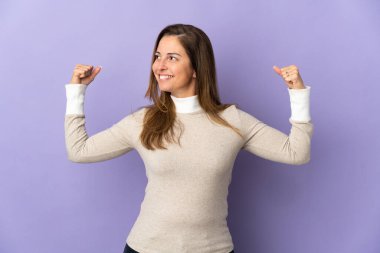 Mor arka planda izole edilmiş orta yaşlı Brezilyalı kadın güçlü bir jest yapıyor.