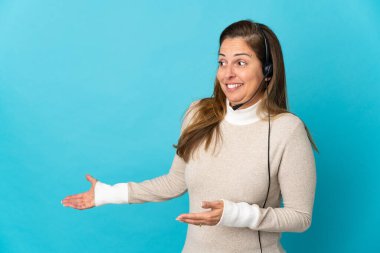 Genç tele pazarlamacı kadın, mavi arka planda, sürpriz bir ifadeyle yan yana bakarken.