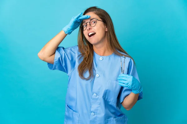 中年牙医巴西妇女拿着工具在孤立的背景下做令人惊讶的手势 同时向侧面看去 — 图库照片