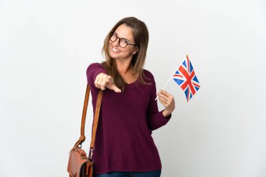 Orta yaşlı Brezilyalı bir kadın beyaz arka planda izole edilmiş bir Birleşik Krallık bayrağı tutuyor ve mutlu bir ifadeyle öne bakıyor.