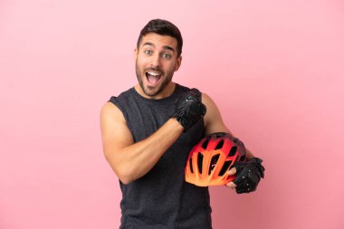 Pembe arka planda izole edilmiş genç bisikletçi zaferi kutluyor.