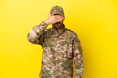 Sarı arka planda izole edilmiş asker gözleri elleriyle kapatıyor. Bir şey görmek istemiyorum.