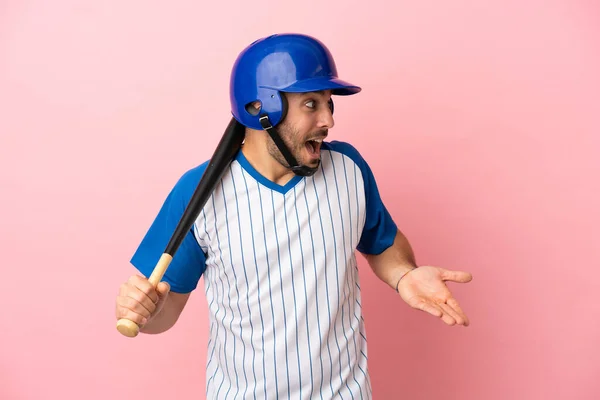 带着安全帽和球棒的棒球手 背景粉红 面带微笑 一边看一边看 — 图库照片
