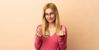 Genç Uruguaylı sarışın kadın soyutlanmış bir şekilde para hareketi yapıyor.