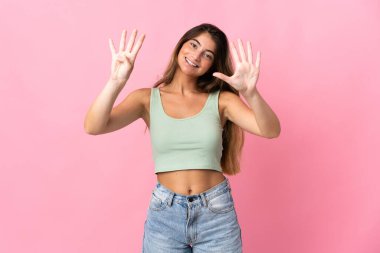 Pembe arka planda izole edilmiş beyaz bir kadın dokuz parmaklı sayıyor.