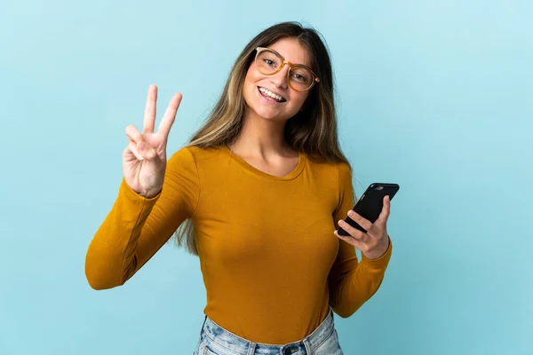 Giovane Donna Caucasica Utilizzando Telefono Cellulare Isolato Sfondo Blu Sorridente — Foto Stock