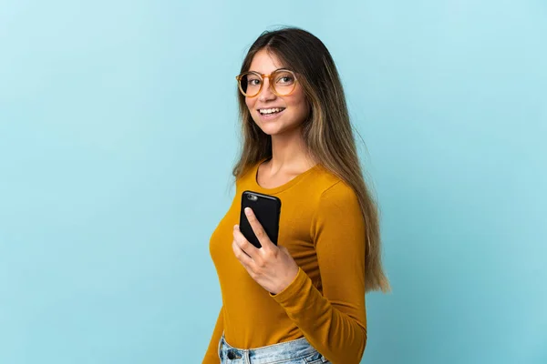 Giovane Donna Caucasica Utilizzando Telefono Cellulare Isolato Sfondo Blu Sorridente — Foto Stock