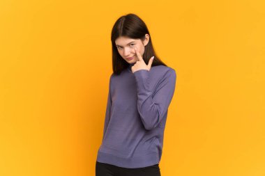 Sarı arka planda izole edilmiş genç Ukraynalı kız bir şey gösteriyor