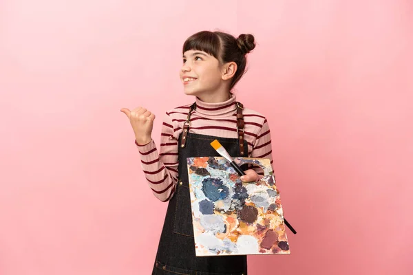 Pequeña Artista Sosteniendo Una Paleta Aislada Sobre Fondo Rosa Apuntando — Foto de Stock