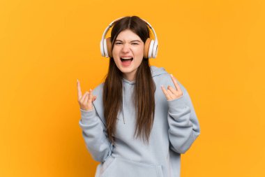 Genç Ukraynalı kız sarı arka planda izole edilmiş rock hareketlerini dinliyordu.