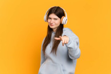 Genç Ukraynalı kız sarı arka planda izole edilmiş müzik dinliyor.