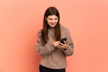 Pembe arka planda izole edilmiş genç Ukraynalı kız cep telefonuyla mesaj ya da e-posta gönderiyor.