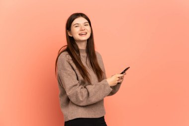 Pembe arka planda izole edilmiş genç Ukraynalı kız cep telefonuyla mesaj ya da e-posta gönderiyor.