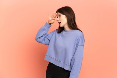 Genç Ukraynalı kız pembe arka planda izole edilmiş sürpriz bir ifadeyle yan tarafa bakarken