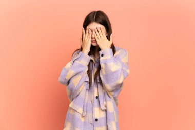 Pembe arka planda izole edilmiş genç Ukraynalı kız gözlerini elleriyle kapatıyor.