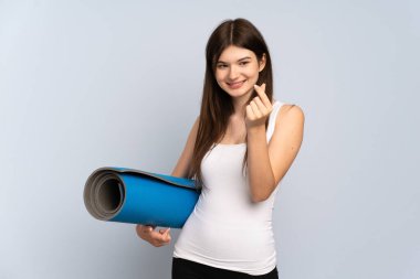 Ukraynalı genç sporcu kız elinde minder tutarak yoga derslerine gidiyor.