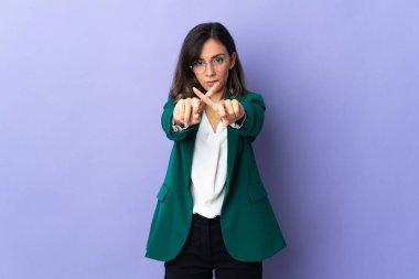 Mor arka planda izole edilmiş genç beyaz kadın bir hareketi durdurmak için eliyle jest yapıyor.