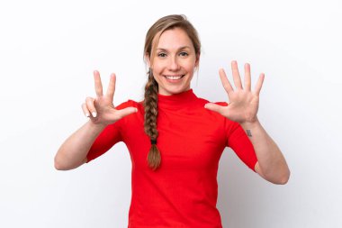 Beyaz arka planda izole edilmiş genç beyaz kadın parmaklarıyla sekizi sayıyor.